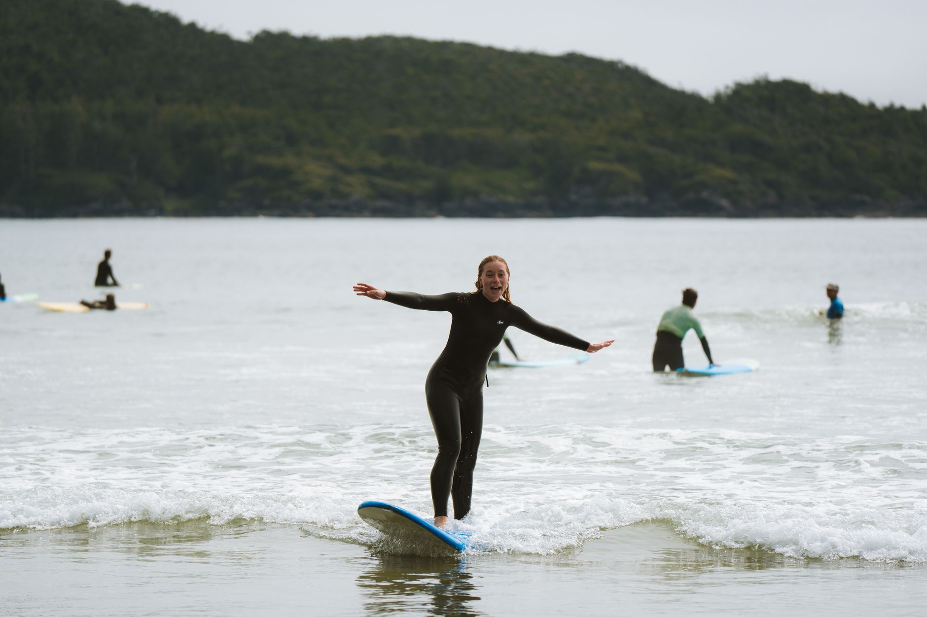 Instructor demonstrating technique to beginners taking their first surf lessons on a UK beach